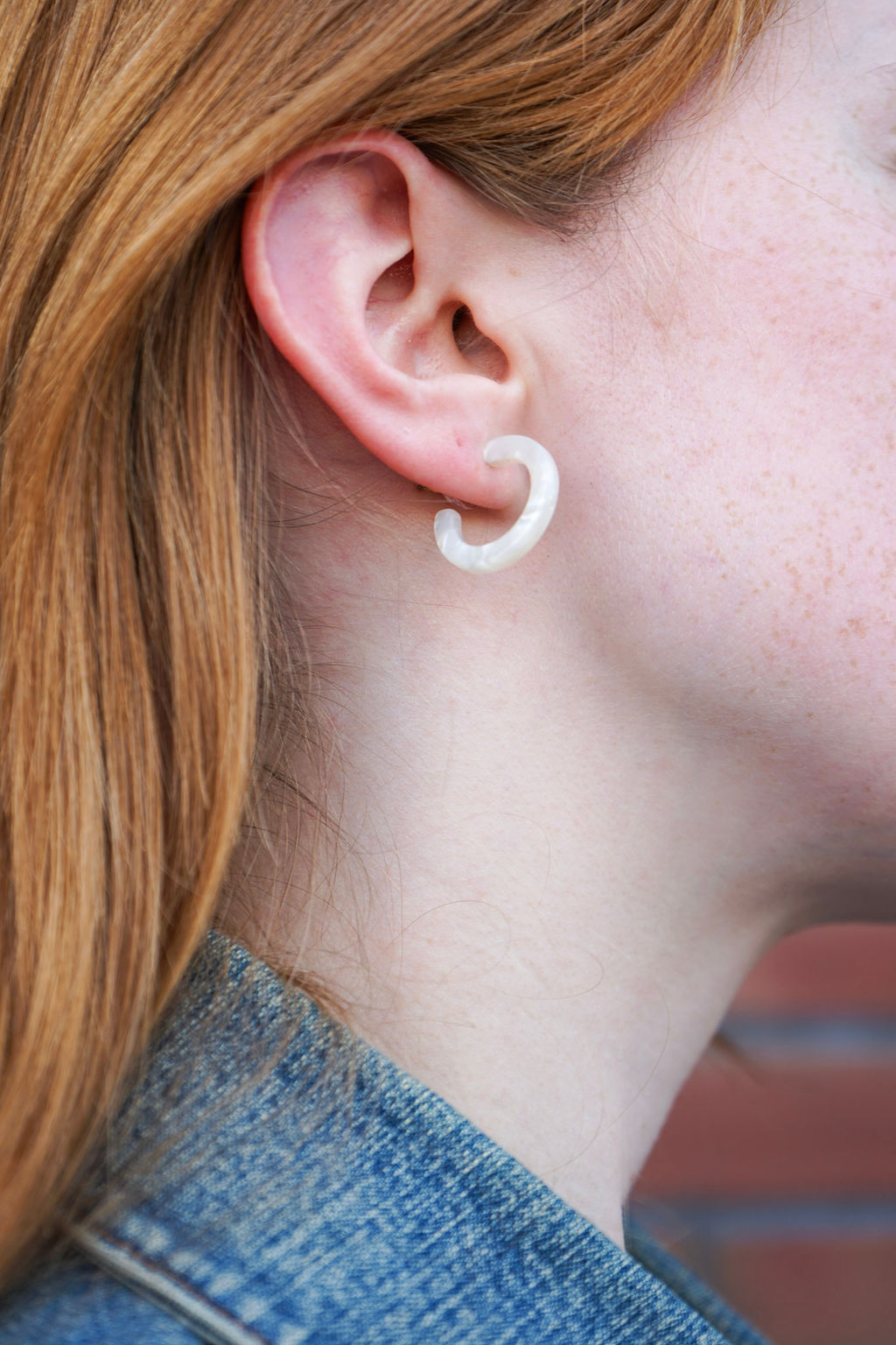 Close-up of a person wearing a white U-shaped earring.