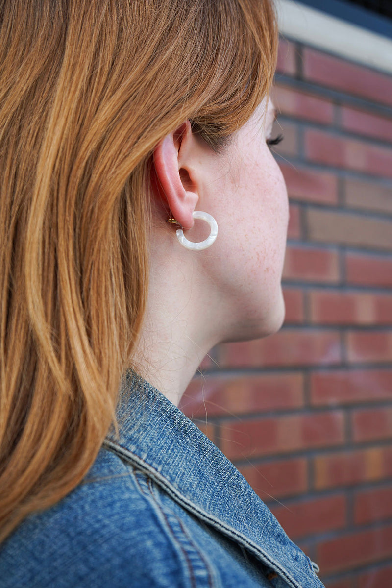 Person wearing a hoop earring with a brick wall background
